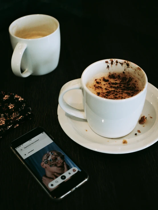 a cup of coffee and a cell phone on a table, a polaroid photo, by Lucia Peka, trending on pexels, happening, faces of too much caffeine, disintegrating, milk and mocha style, profile image