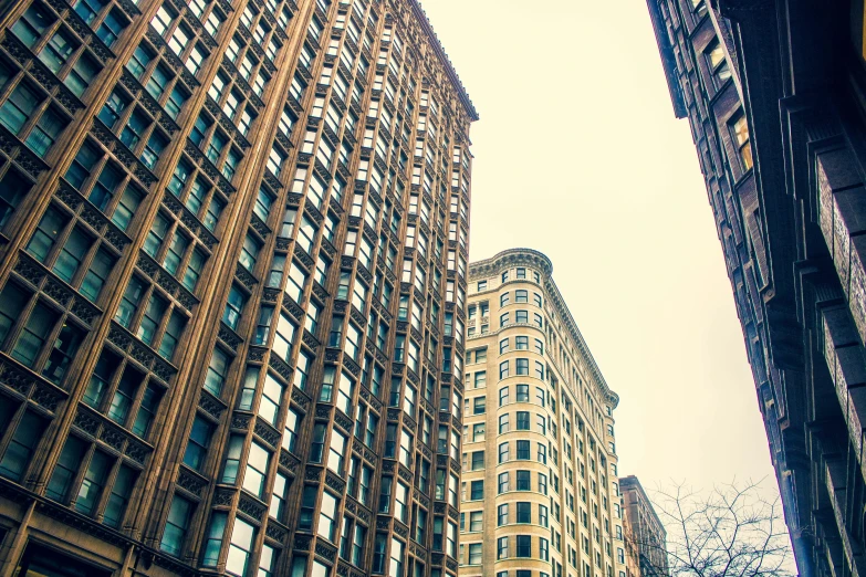 a couple of tall buildings next to each other, a photo, by Greg Rutkowski, unsplash, art nouveau, square, grain”, 1 9 0 0 ’ s photo ”, low angle photograph