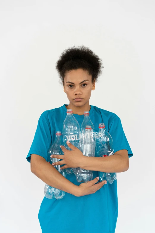 a woman in a blue shirt holding a bottle of water, an album cover, by Christopher Williams, grime, plastic bottles, nonbinary model, photographed for reuters