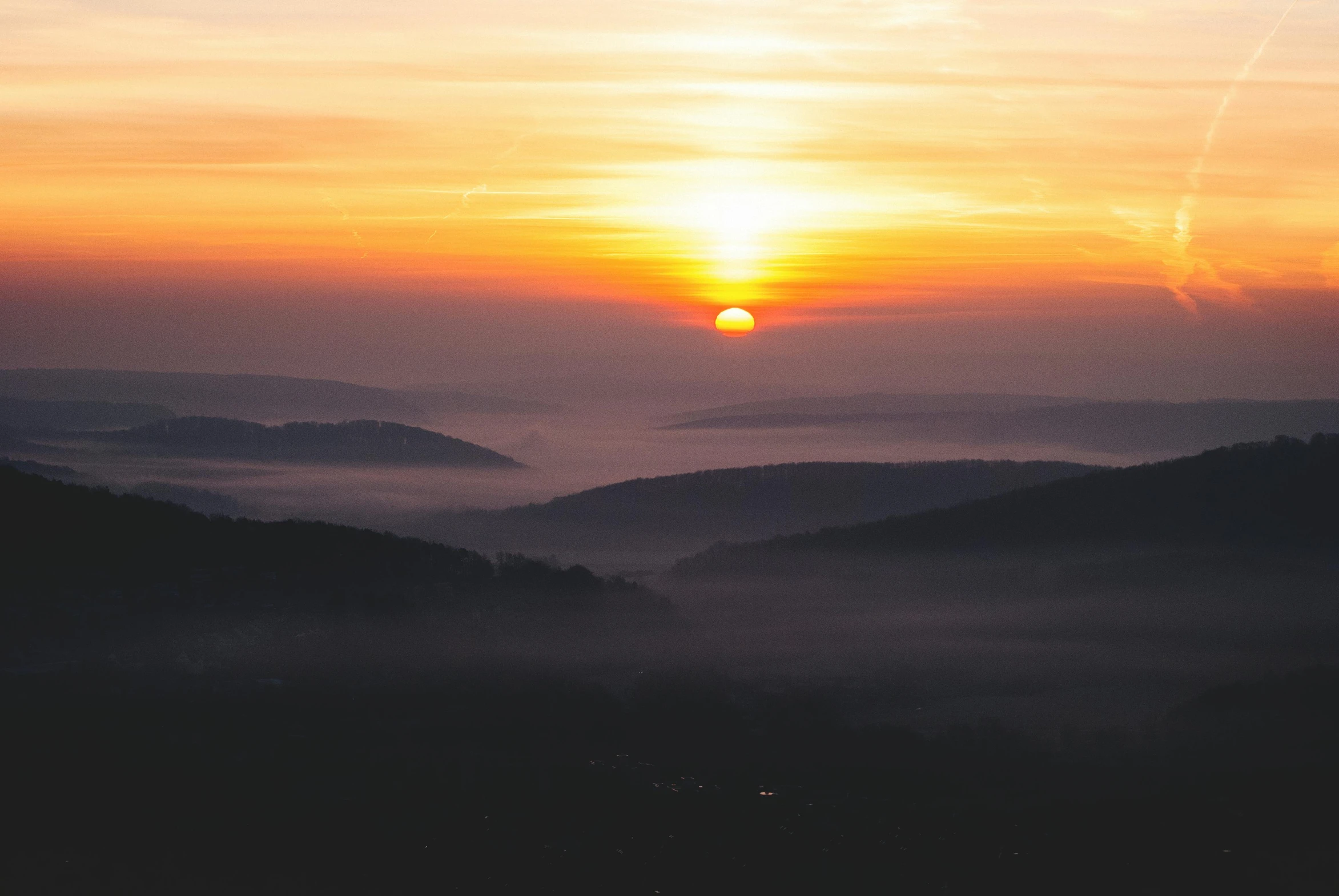 the sun is setting over the mountains in the distance, pexels contest winner, romanticism, hazy morning foggy, william penn state forest, ((sunset)), grey