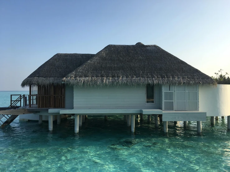 a house in the water with a thatched roof, unsplash, hurufiyya, maldives in background, profile image, john pawson, hotel room