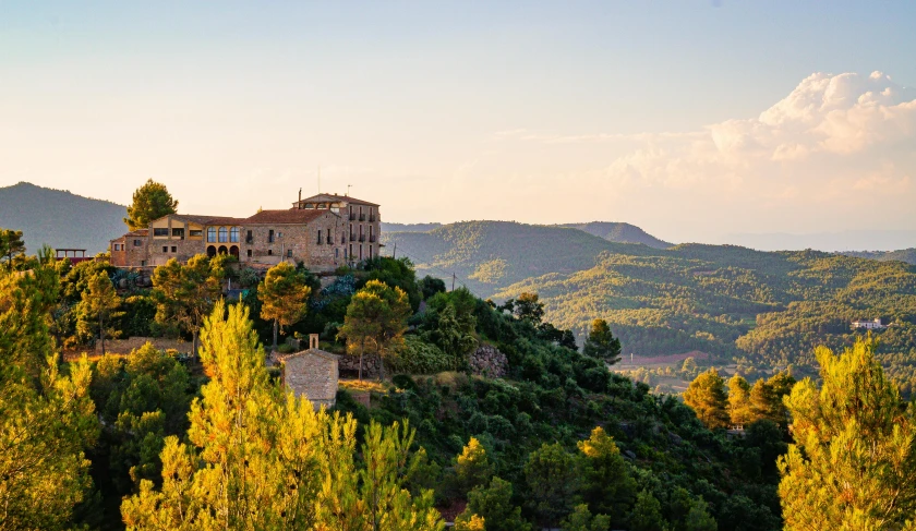 a large building sitting on top of a lush green hillside, les nabis, pink golden hour, albert ramon puig, conde nast traveler photo