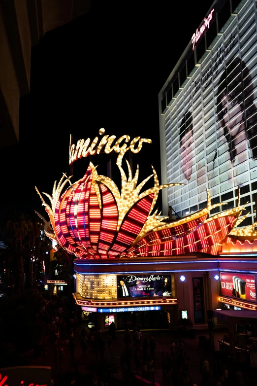 a large neon sign on the side of a building, django, las vegas at night, lumnious, seen from below