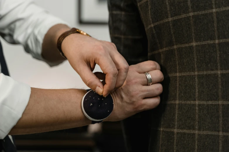 a close up of a person putting a watch on another person's wrist, by Emma Andijewska, old wool suit, curated collections, belly button showing, stitching