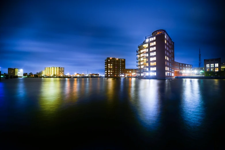 a large body of water with buildings in the background, by Peter Churcher, pexels contest winner, hull, flood lighting, helmond, blue