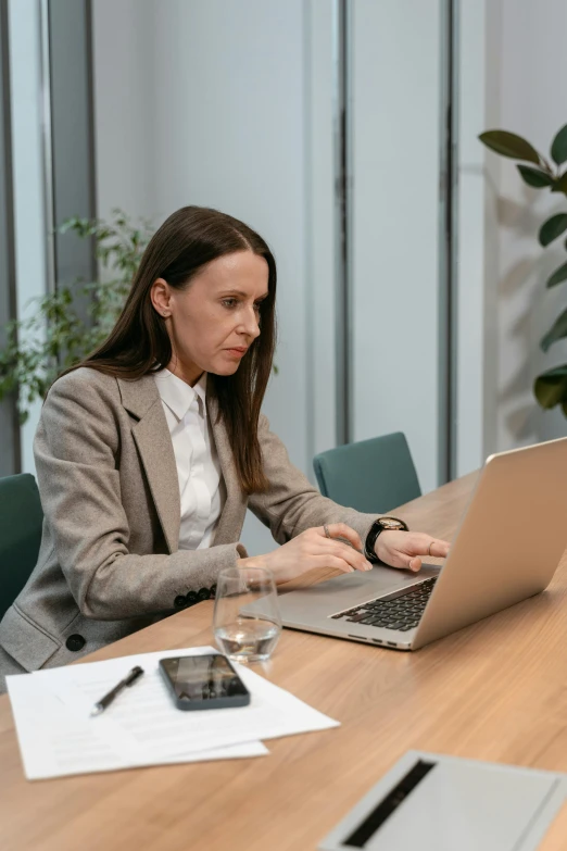 a woman sitting at a table working on a laptop, pexels contest winner, in a meeting room, low quality photo, thumbnail, 8