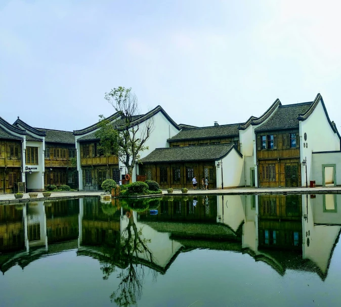 a building with a pond in front of it, inspired by Wang Yi, pexels contest winner, white houses, peaked wooden roofs, private school, conde nast traveler photo