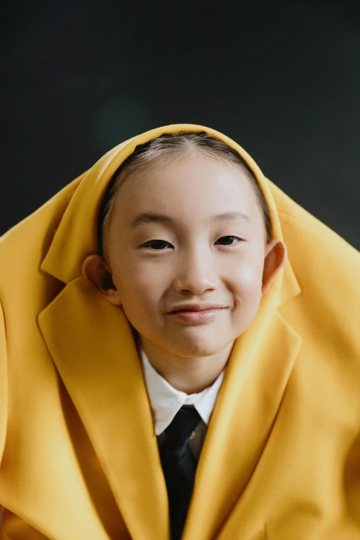 a young boy wearing a yellow coat and tie, an album cover, inspired by Kim Tschang Yeul, unsplash, hyperrealism, happy girl, religious robes, covered head, photographed for reuters