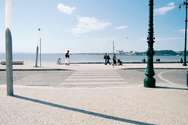 a group of people riding skateboards down a street, a picture, inspired by Almada Negreiros, lake view, tiles, beachfront, lampposts