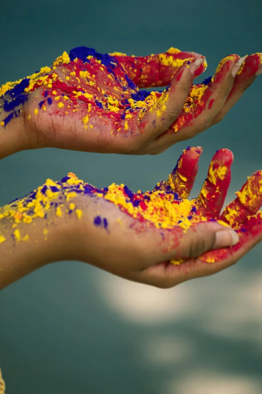 a close up of a person's hands covered in paint, inspired by Steve McCurry, hands which exchange seeds, red yellow blue, color”