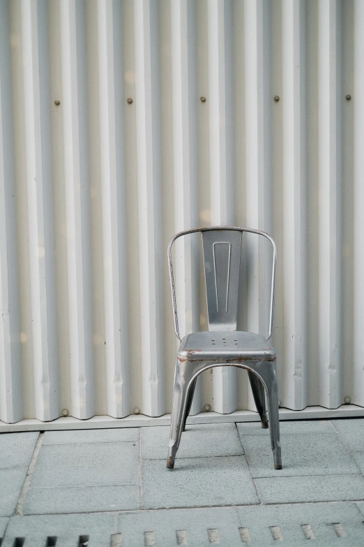 a metal chair sitting in front of a metal wall, unsplash, white background, multiple stories, galvalume metal roofing, in 2 0 1 5