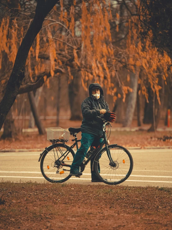 a person wearing a face mask riding a bike, by Attila Meszlenyi, pexels contest winner, realism, late autumn, wide full body, thoughtful, rectangle