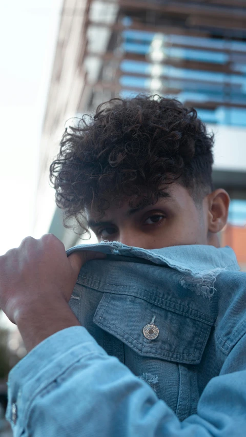 a close up of a person holding a cell phone, an album cover, by Adam Dario Keel, curly and short top hair, wearing double denim, undercut, lgbtq