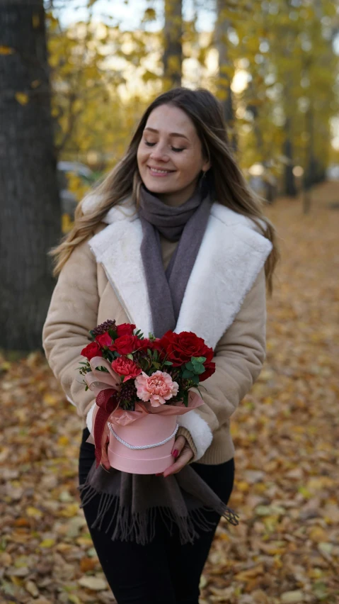 a woman holding a bouquet of flowers in a park, by Anna Katharina Block, pexels, red leather short coat, brown and pink color scheme, 15081959 21121991 01012000 4k, november