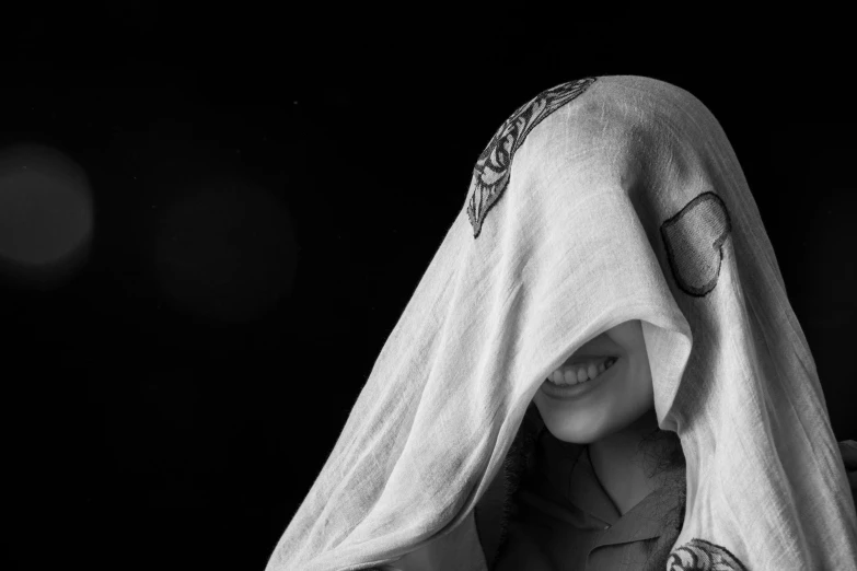 a black and white photo of a woman wrapped in a towel, by Adam Marczyński, pixabay contest winner, hooded skull, six from little nightmares, smile like a sphinx, studio shoot