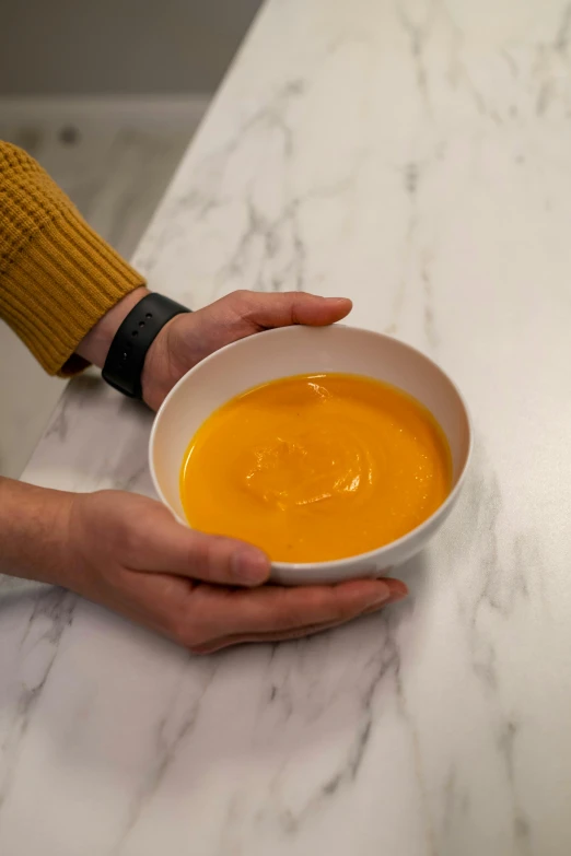 a person holding a bowl of soup on a counter, very orange, detailed product image, extremely polished, thumbnail