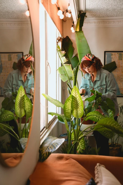 a woman sitting on a couch in front of a mirror, a photo, inspired by Elsa Bleda, detailed plant life, gardening, 6 : 3 0 am, tropical style