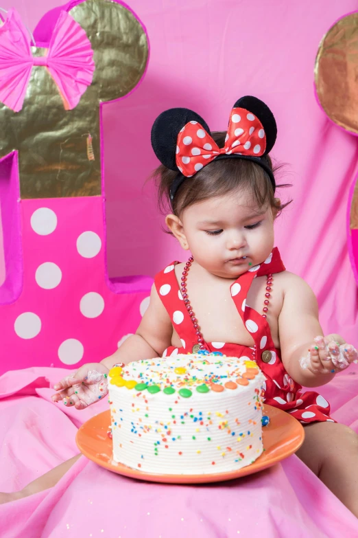 a little girl that is sitting in front of a cake, minnie mouse, bright vivid color hues:1, profile image