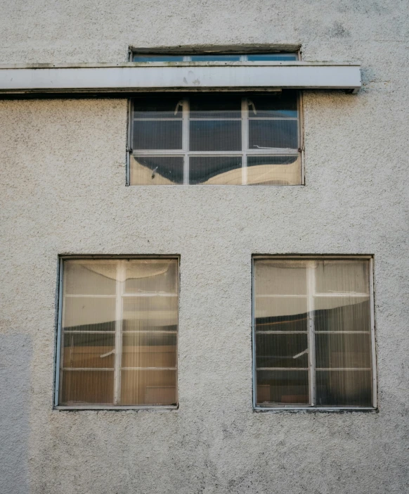 a couple of windows sitting on the side of a building, an album cover, by Attila Meszlenyi, unsplash, modernism, concrete steel glass, apartment of an art student, taken in the early 2020s, low iso