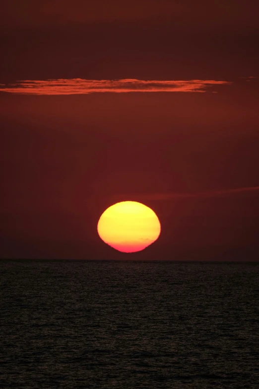 the sun is setting over the ocean, bright yellow and red sun, photograph, round-cropped, f / 2 0