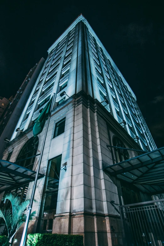 a tall building is lit up at night, dark teal lighting, white marble buildings, dramatic lighting - n 9, high-quality photo