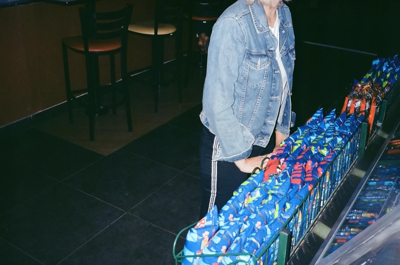 a woman standing in front of a conveyor belt full of soda bottles, an album cover, inspired by Elsa Bleda, unsplash, hyperrealism, wearing blue jean overalls, getting groceries, gif, night photo