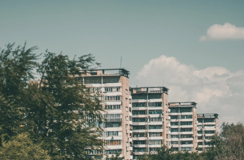 a tall building sitting on top of a lush green field, by Emma Andijewska, unsplash contest winner, brutalism, soviet apartment buildings, 000 — википедия, in retro colors, panorama