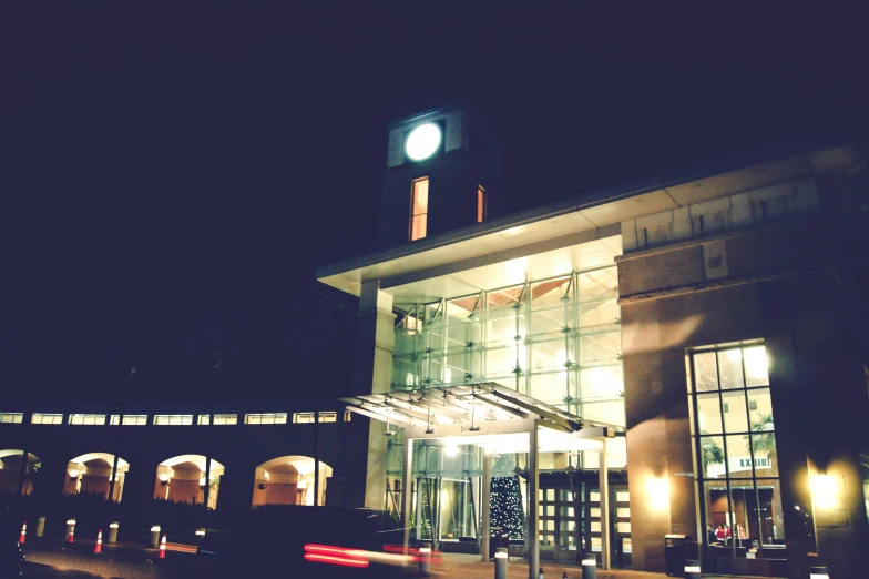 a building with a clock tower lit up at night, a photo, hurufiyya, southdale center, 💋 💄 👠 👗, cosy, entrance