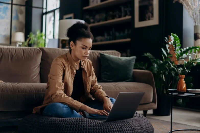 a woman sitting on a couch using a laptop, pexels, tessa thompson, hunting, developers, brown