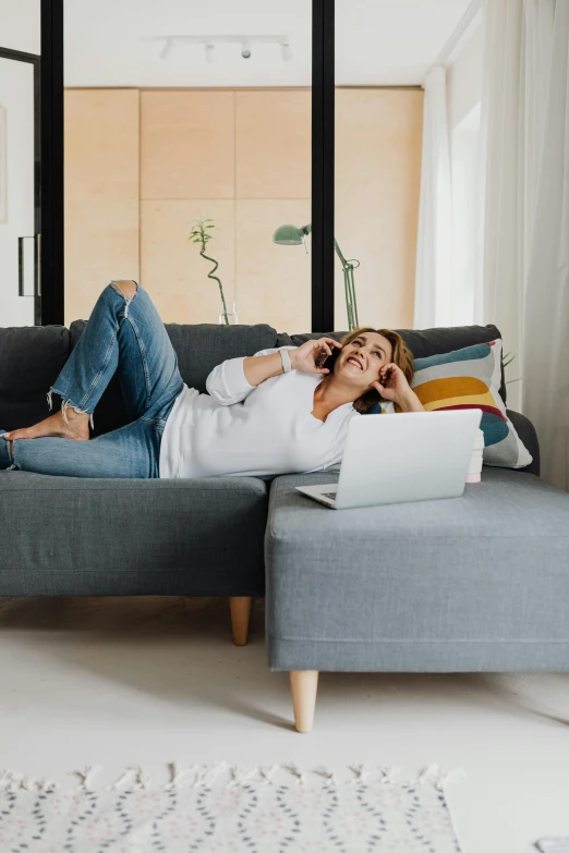 a woman laying on a couch with a laptop, trending on pexels, girl making a phone call, wide full body, comfy chairs, white shirt and jeans