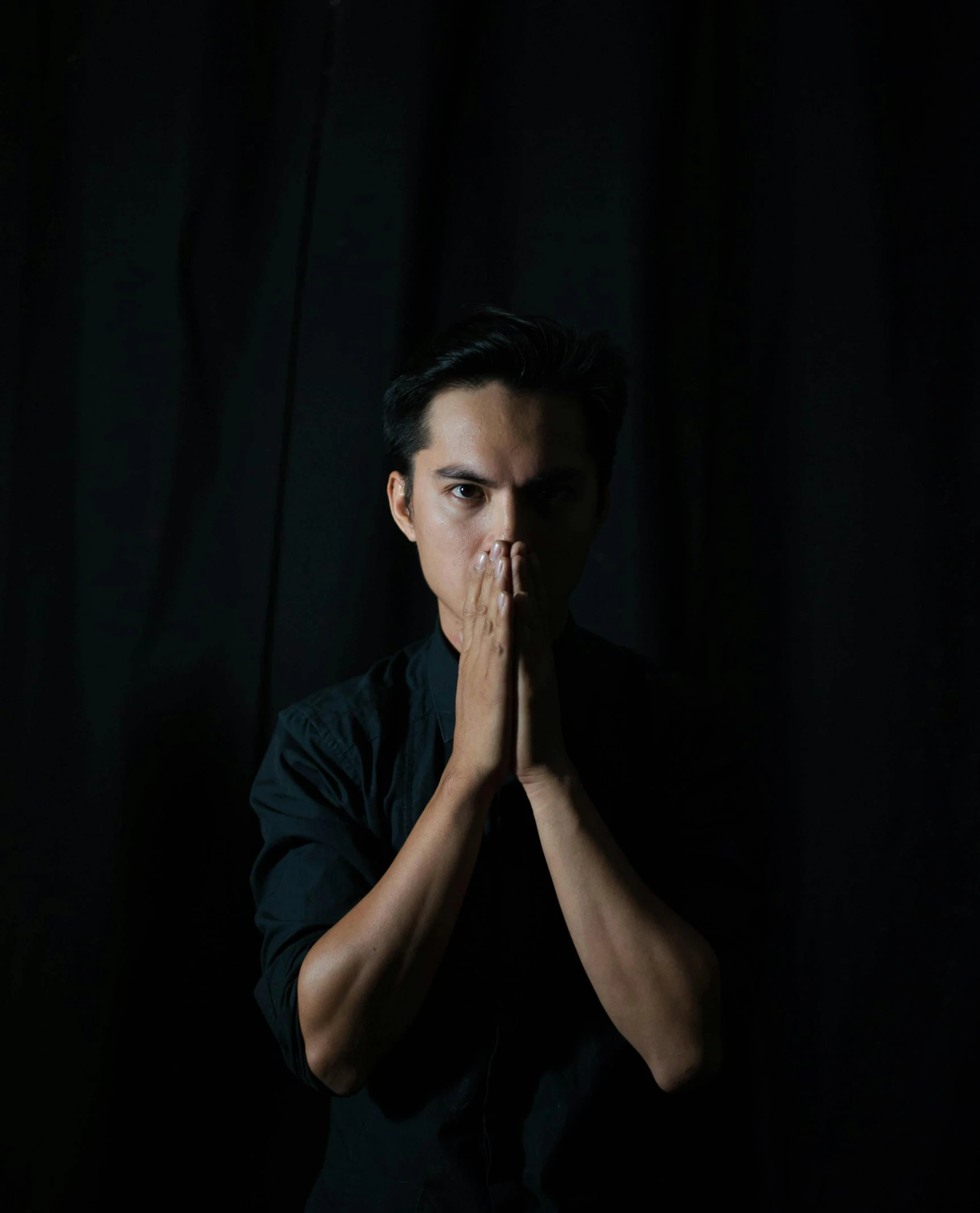 a man in a black shirt covers his face with his hands, an album cover, by Robbie Trevino, unsplash, sumatraism, joe taslim, lgbtq, doing a prayer, profile picture