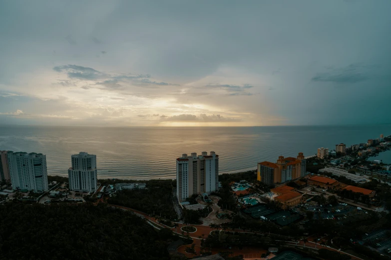 a view of the ocean from the top of a building, unsplash contest winner, realism, sunset lighting 8k, sun coast, view from helicopter, overcast lighting