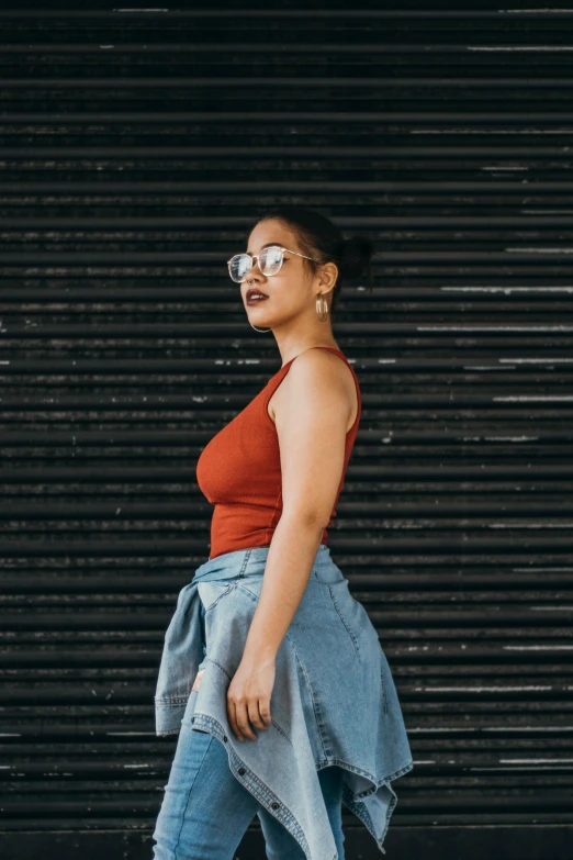 a woman in a red top is walking down the street, an album cover, inspired by Ruth Jên, pexels contest winner, renaissance, thick glasses, wearing : tanktop, leaning against the wall, at a fashion shoot