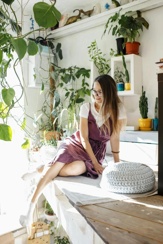 a woman sitting on a kitchen counter next to a potted plant, maximalism, sunflare, terrarium lounge area, profile image, cindy avelino