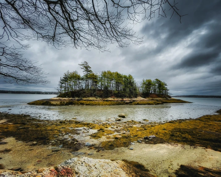 a small island in the middle of a body of water, by Jessie Algie, unsplash, land art, overcast gray skies, new hampshire, many islands, conde nast traveler photo
