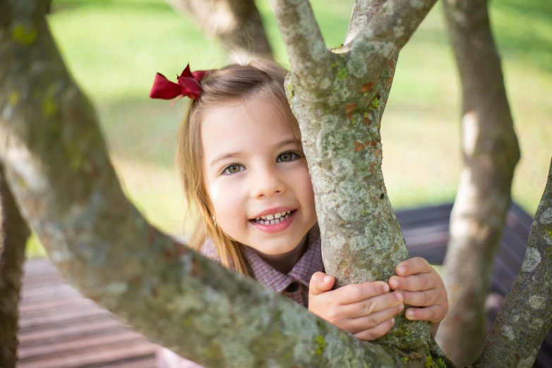 a little girl that is sitting in a tree, while smiling for a photograph, private school, avatar image, andrew tate