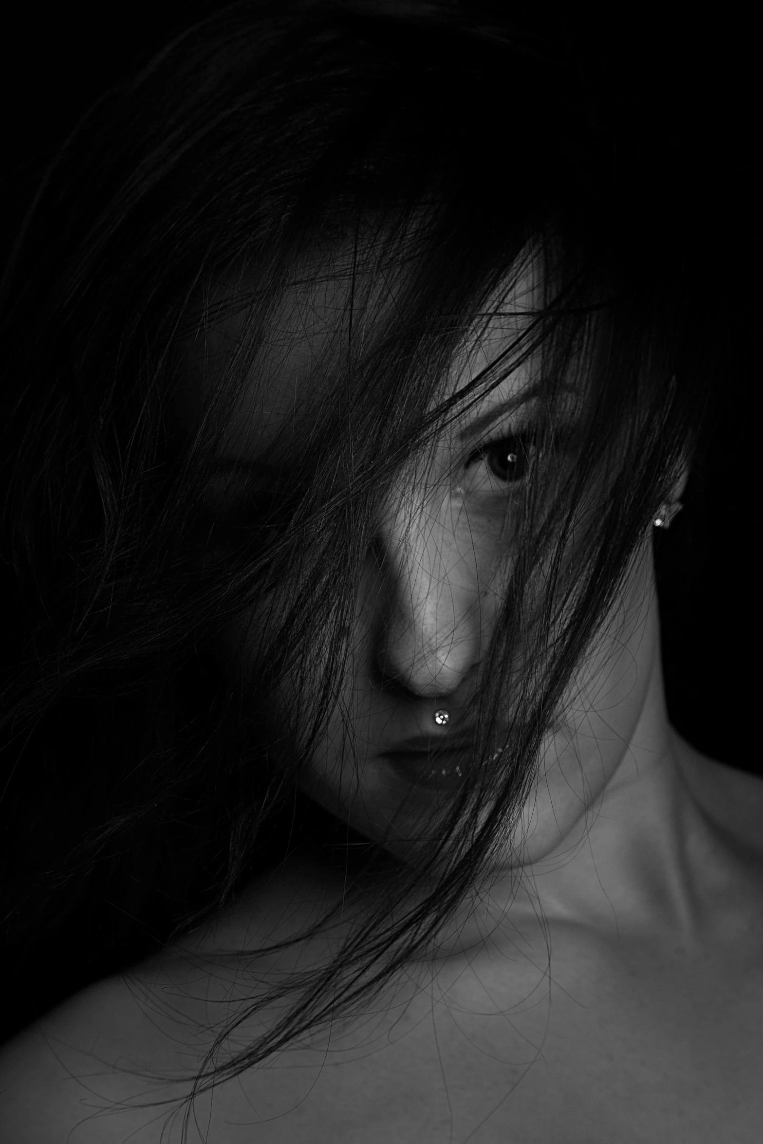 a black and white photo of a woman with her hair blowing in the wind, by Adam Marczyński, pexels contest winner, with anxious piercing eyes, with haunted eyes and dark hair, woman with black hair, noseless