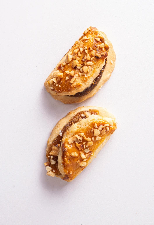 a couple of sandwiches sitting on top of a white table, walnuts, detailed product image, pastelle, half turned around