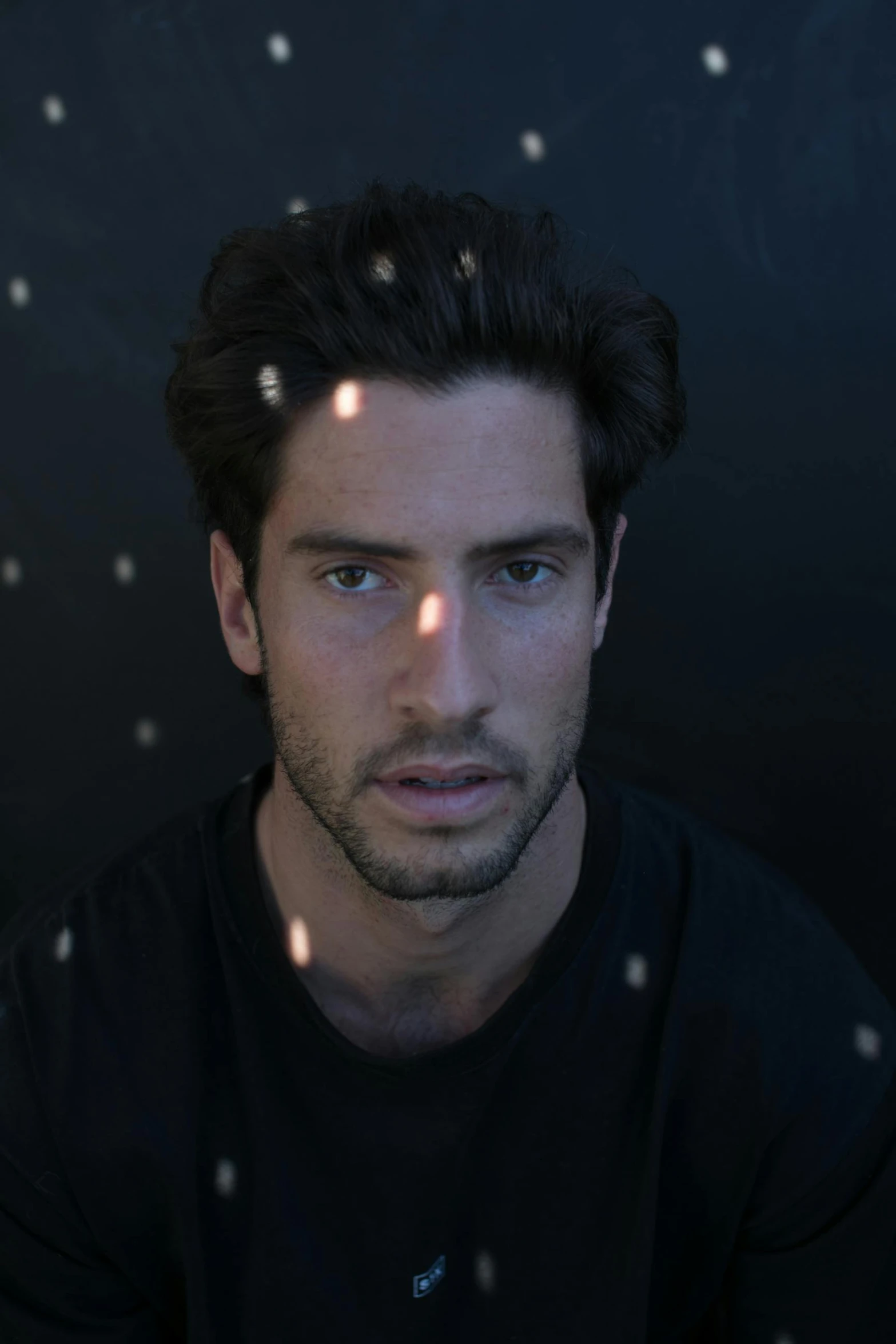 a man sitting in front of a black background, with amber eyes, daniel mirante, dreamy, greg rutowski