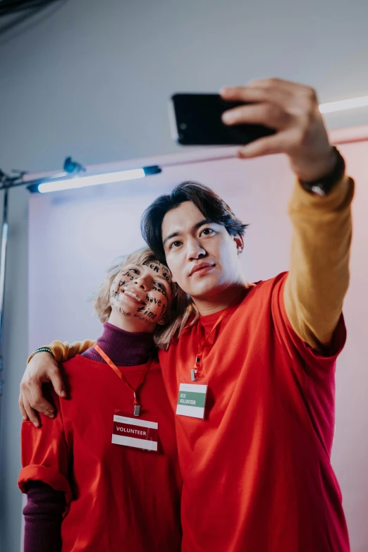 a man and a woman taking a selfie, a polaroid photo, by Jang Seung-eop, trending on pexels, realism, wearing red clothes, nonbinary model, bright daylight indoor photo, yearbook photo