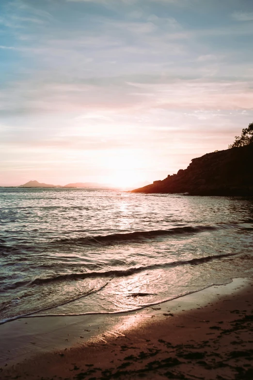 a large body of water sitting on top of a sandy beach, inspired by Edwin Deakin, unsplash, romanticism, pink golden hour, photographed on colour film, wellington, island landscape