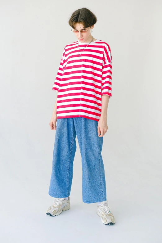 a woman standing in front of a white wall wearing a red and white striped shirt, by Eizan Kikukawa, unsplash, baggy jeans, model エリサヘス s from acquamodels, for kids, red t-shirt