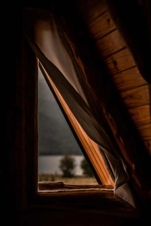 a window with a view of a body of water, by Peter Churcher, unsplash contest winner, peaked wooden roofs, dramatic lighting - n 9, cabin, brown