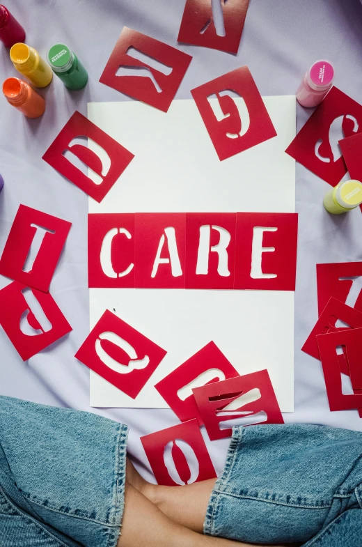 a person holding a sign that says care, a silk screen, inspired by Jim Dine, trending on pexels, international typographic style, red flags, toys, healthcare worker, papers on table