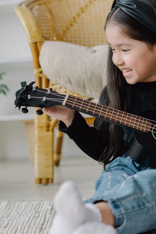 a little girl sitting on the floor playing a guitar, pexels contest winner, incoherents, ukulele, manuka, panoramic view of girl, close up shot from the side