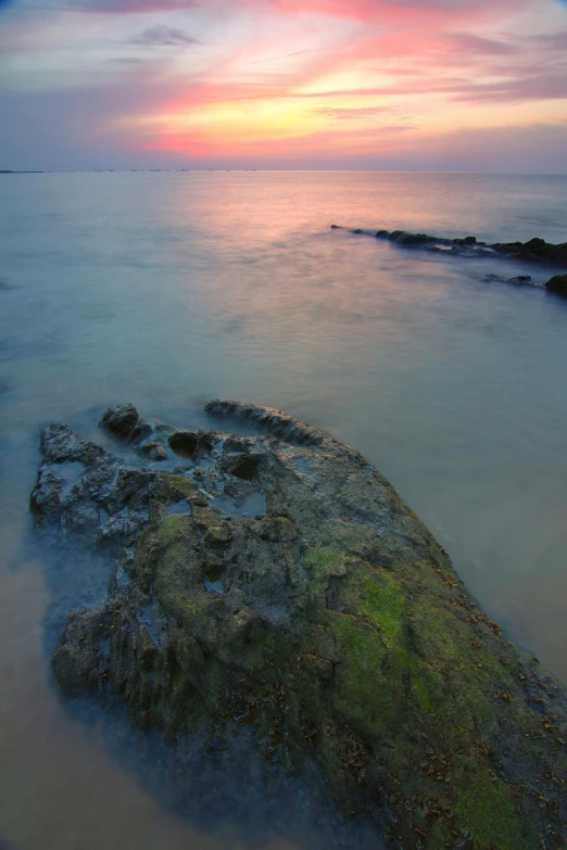 a large rock sitting in the middle of a body of water, by Basuki Abdullah, sunset beach, soft light - n 9, jakarta, coastal