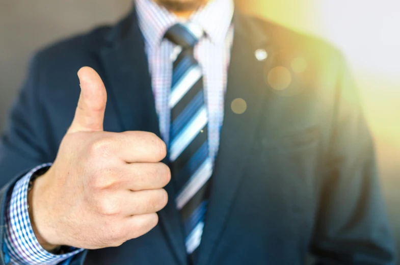 a man in a suit giving a thumbs up, private press, sun shining, colour corrected, best practice, conservatively dressed