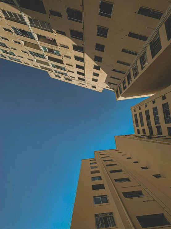 a couple of tall buildings sitting next to each other, inspired by Alexander Rodchenko, unsplash contest winner, clear blue sky, overview, concrete housing, looking upwards