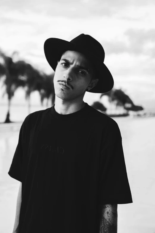 a black and white photo of a man wearing a hat, inspired by Alexis Grimou, mrbeast, small lips pointy nose, beachfront, young prince