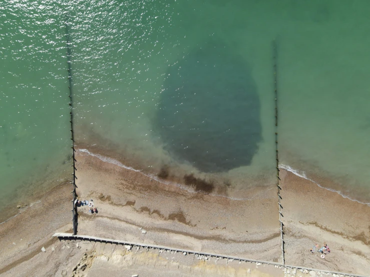 a large body of water next to a beach, by Jan Rustem, unsplash, land art, sunken eyes, made of oil and water, david a trampier, taken on a 2010s camera